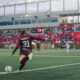 AFC Toronto player Colby Barnett takes a corner kick. Fans occupy the stands in front of her.