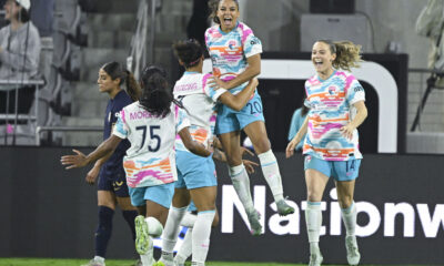 Delphine Cascarino jumps in the air and celebrates a goal with her teammates.